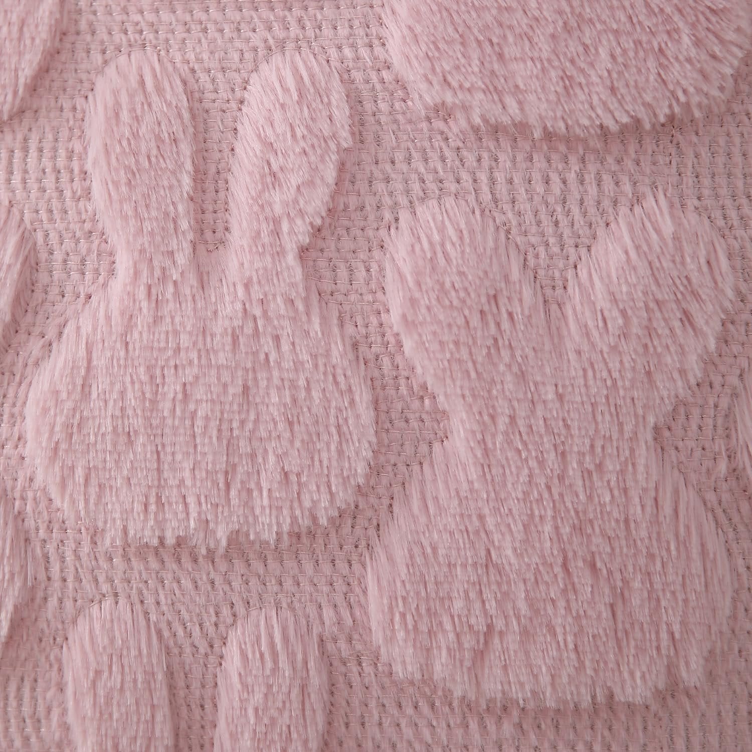 Close-up of pink plush faux fur pillow cover with jacquard bunny pattern and textured weave.