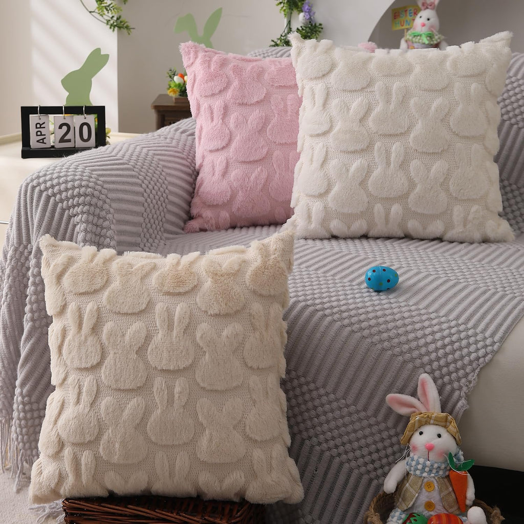 Three plush Easter bunny throw pillow covers in pink and cream arranged on a sofa with a decorative calendar and stuffed bunny.
