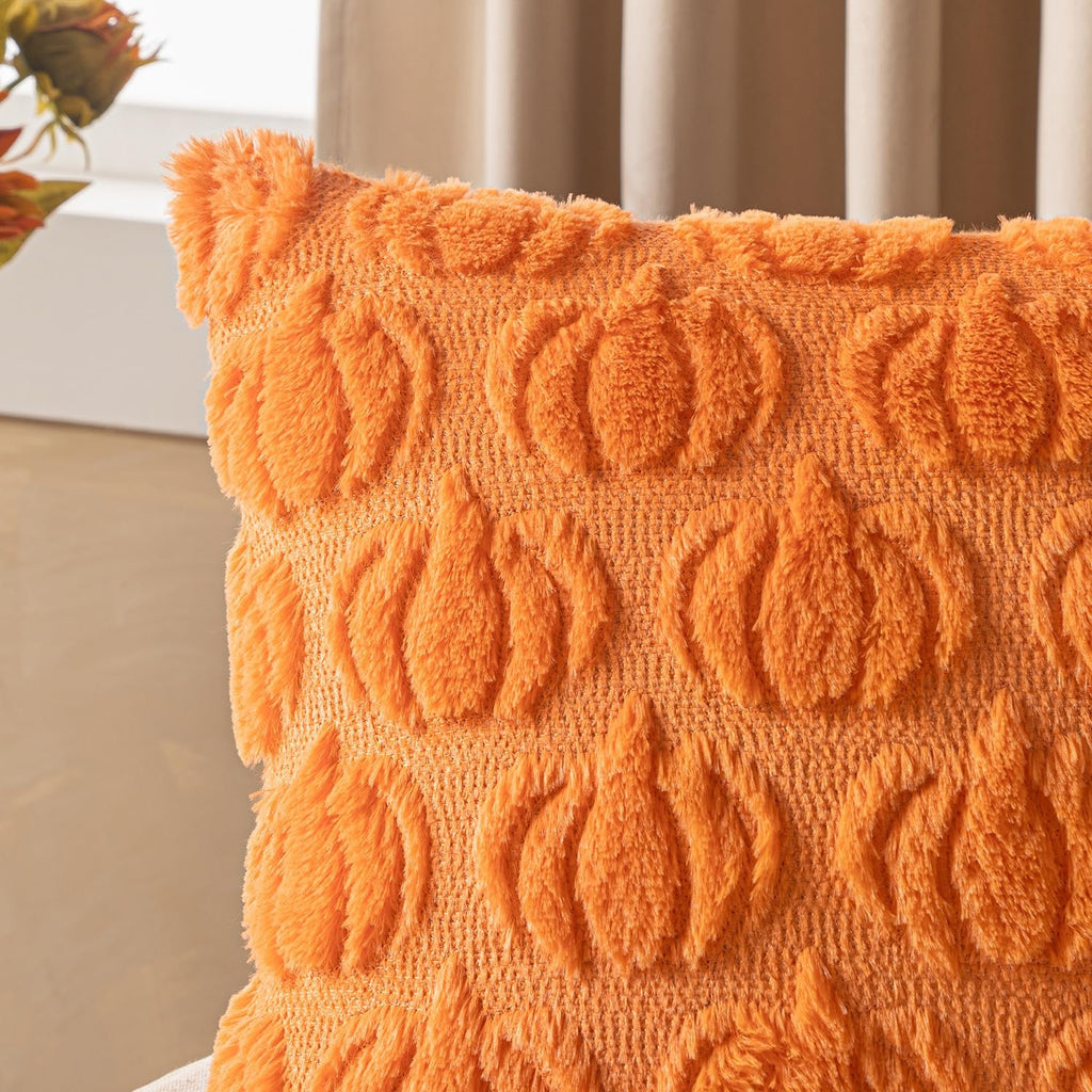 Close-up of an orange faux fur pillow cover with embossed pumpkin pattern, showing texture and detail.