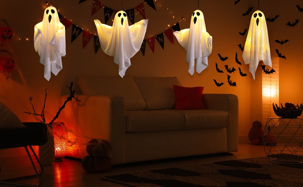 Four hanging light-up ghost decorations with warm white LEDs in a dimly lit room decorated for Halloween.