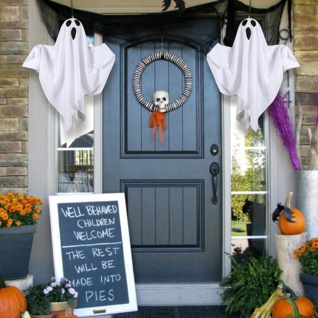 Hanging ghost decorations flank a front door with a Halloween wreath and a chalkboard sign.