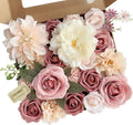 Dusty blush pink artificial rose bouquet set with various flowers and green leaves in a cardboard box.
