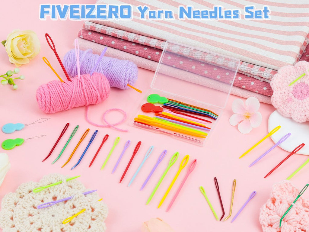 Assorted yarn needles and knitting supplies arranged on a pink background with fabric and yarn.