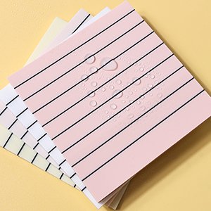 Stack of multicolor lined transparent sticky notes with water droplets on the top sheet