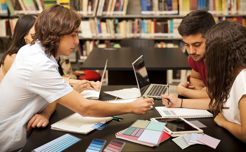 Students studying at a table with laptops and notebooks, with transparent sticky notes and color swatches in the foreground.