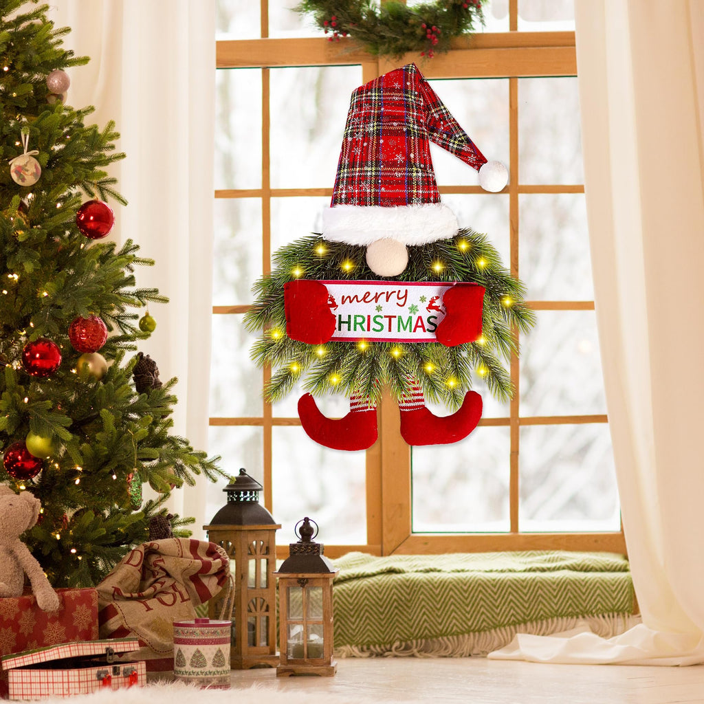 Christmas gnome wreath with plaid hat and red boots hanging on a window with a Christmas tree and gifts nearby