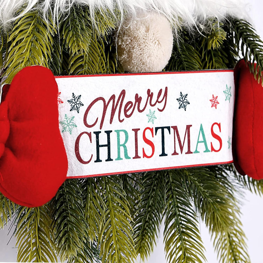 Close-up of a Christmas gnome wreath with red mittens and a Merry Christmas sign surrounded by pine branches.