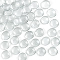 Scattered clear flat glass marbles on a white background, showing their rounded tops and flat bottoms.