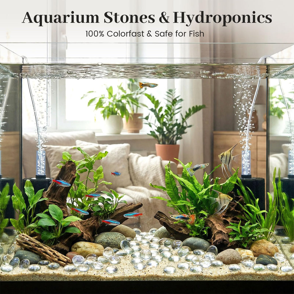 Aquarium with clear glass marbles, fish, plants, and driftwood on a sandy substrate.