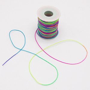 Spool of rainbow elastic beading cord with strands unspooled on a white background