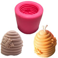 Pink silicone beehive mold with two finished beehive-shaped candles, one beige with a bee, one yellow with flowers.