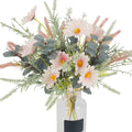 Artificial pink daisy and eucalyptus bouquet in a clear glass vase with a black label