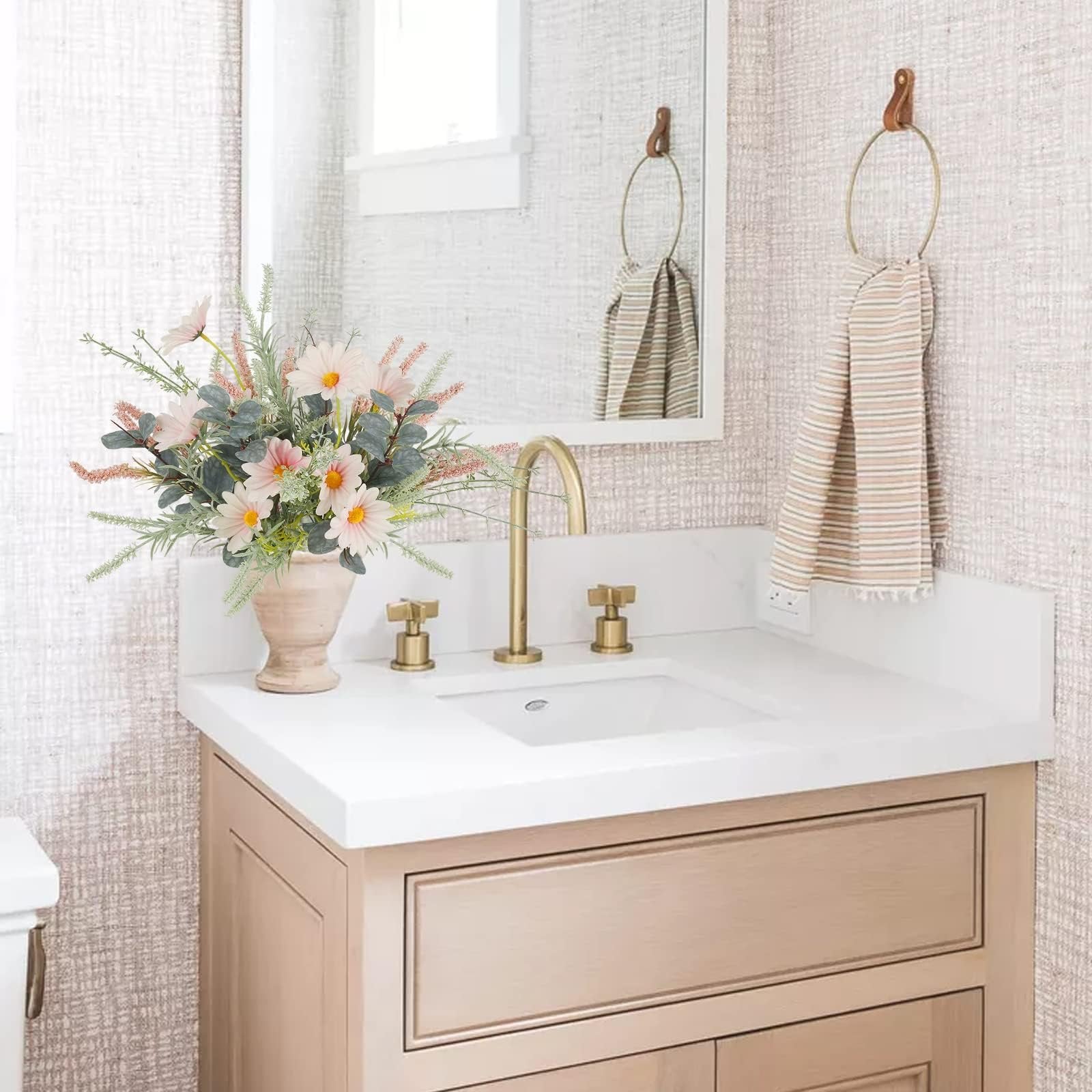 Artificial wildflower bouquet with pink daisies and eucalyptus in a vase on a bathroom vanity