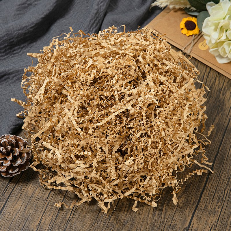 Pile of crinkle cut paper shred filler on a wooden surface with decorative elements