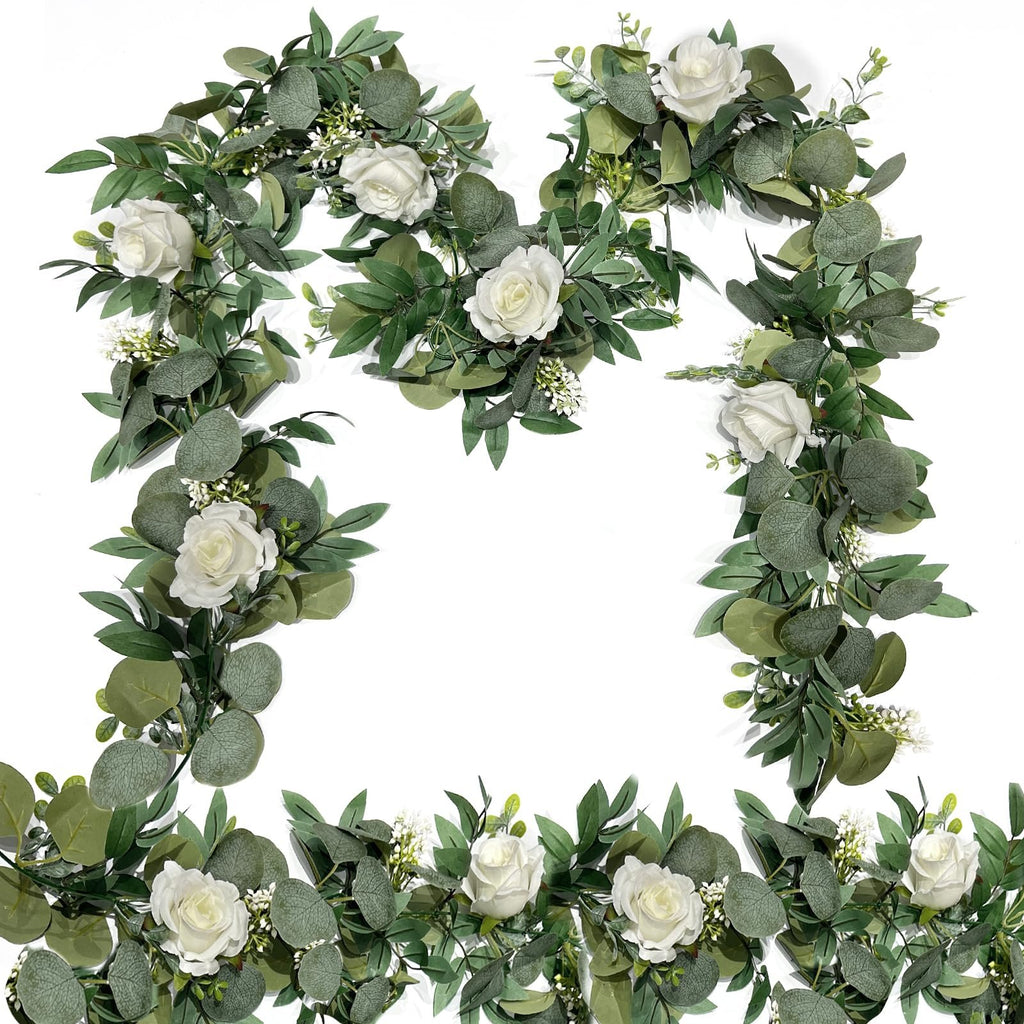 Artificial eucalyptus and white rose garland arranged in a decorative frame on a white background.