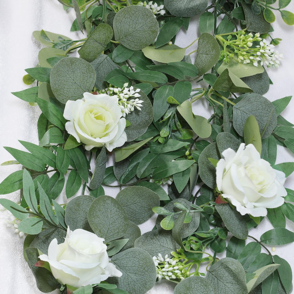 Artificial eucalyptus garland with white roses and small white flowers, close-up view