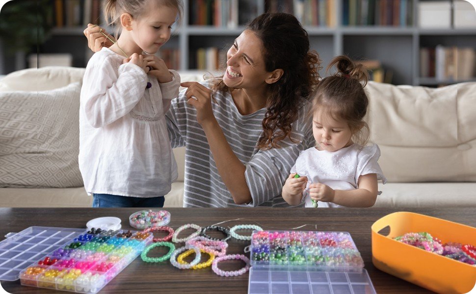 Mother and two daughters making jewelry with colorful beads and charms on a table