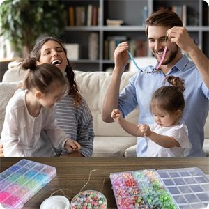 Family of four laughing and making jewelry with colorful glass beads and charms at home