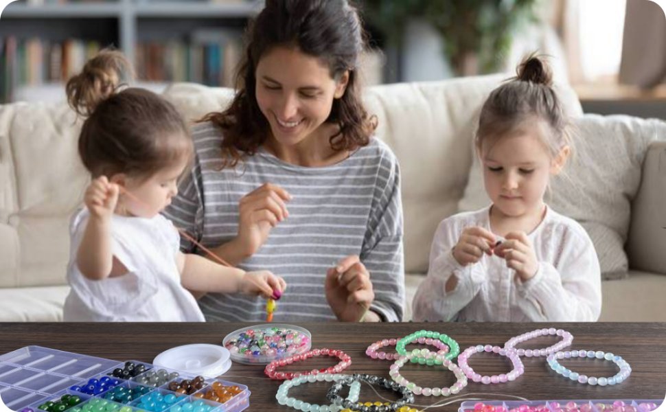 Mother and two daughters making bracelets with colorful glass beads and elastic strings at a table.