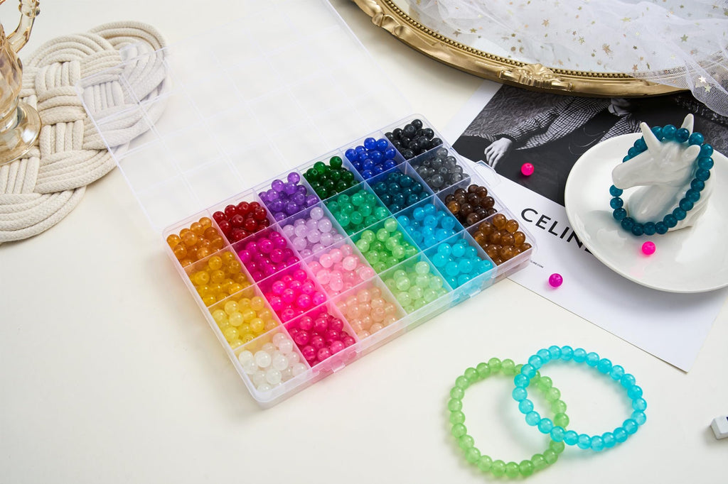 Open bead organizer box filled with colorful 8mm round glass beads, with bracelets and a magazine in the background.