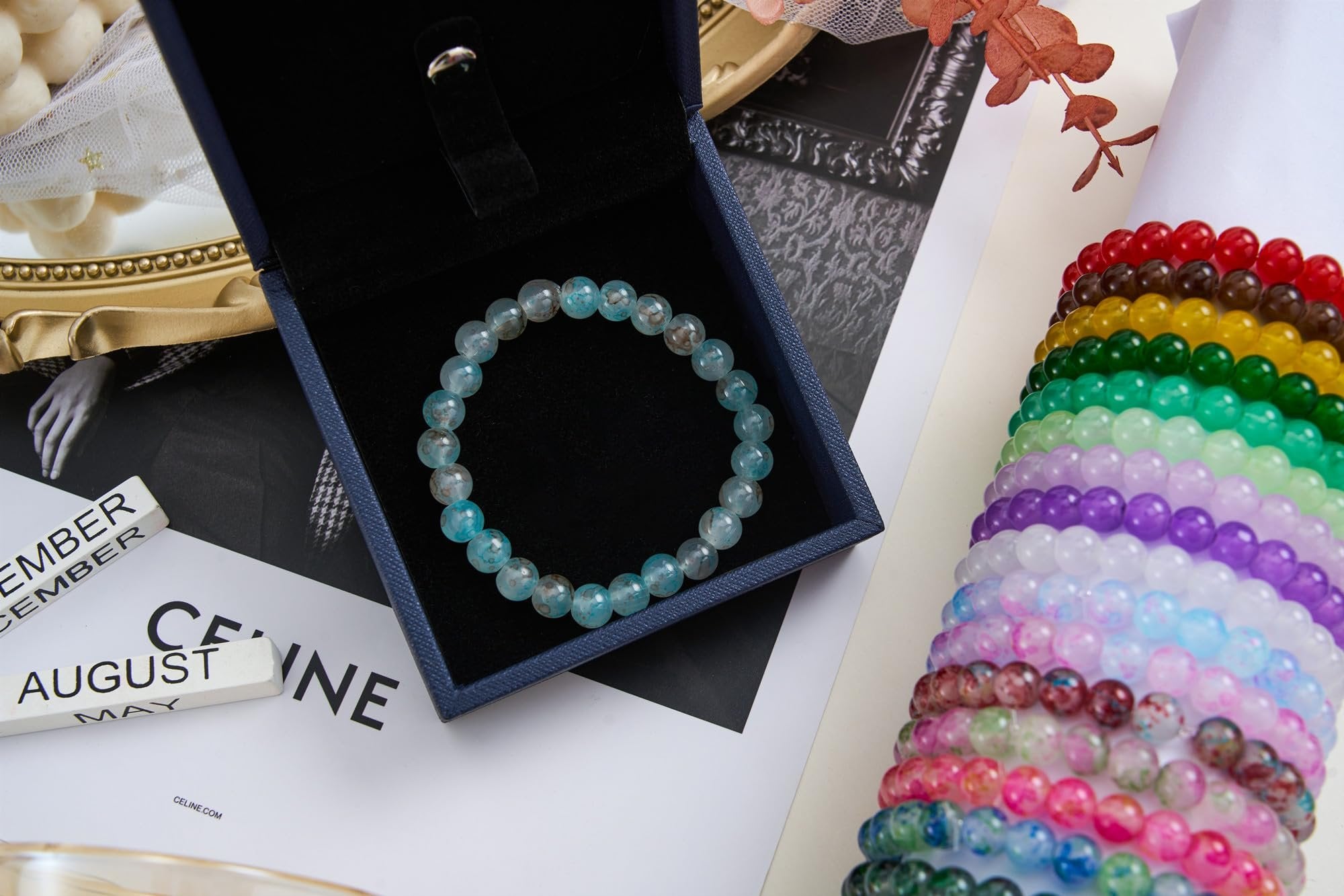 Assortment of colorful glass bead bracelets, one light blue bracelet displayed in a dark blue jewelry box.