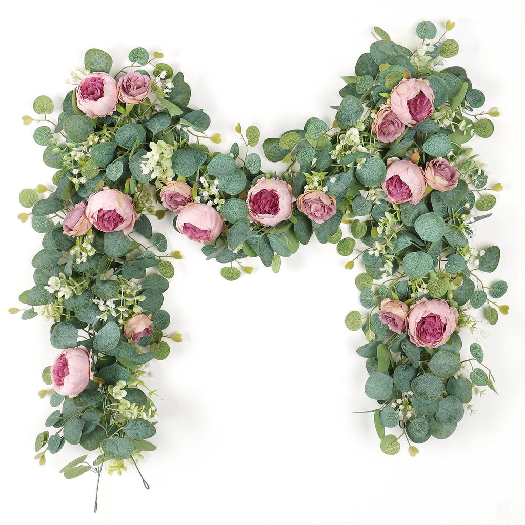 Artificial peony and rose garland with eucalyptus leaves and small white flowers, arranged in an arch shape on a white background.