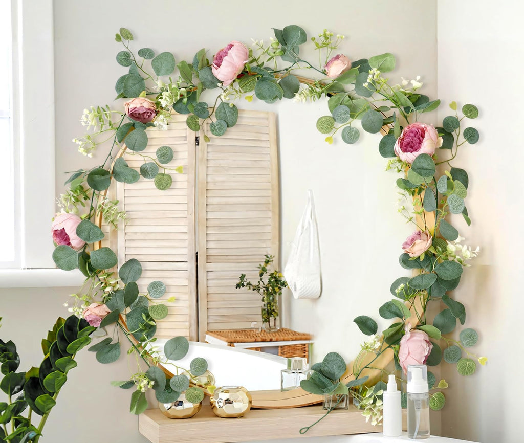 Artificial peony and eucalyptus garland draped around a mirror in a bathroom setting.