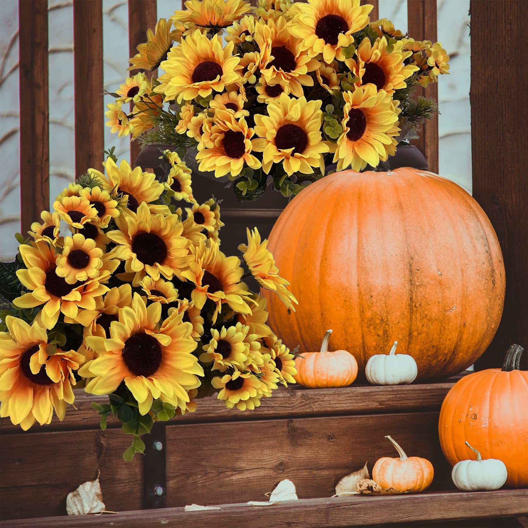 Two bouquets of artificial sunflowers with eucalyptus and fern grass arranged with pumpkins on wooden steps