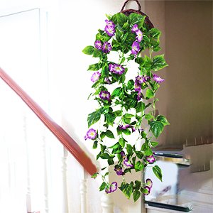 Purple artificial morning glory vine garland with green leaves hanging from a basket on a staircase railing.