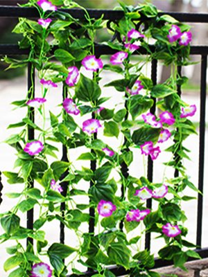 Artificial morning glory vine garland with purple and white flowers draped over a black railing.