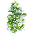 Artificial morning glory vine garland with light blue and purple flowers and green leaves, isolated on white.