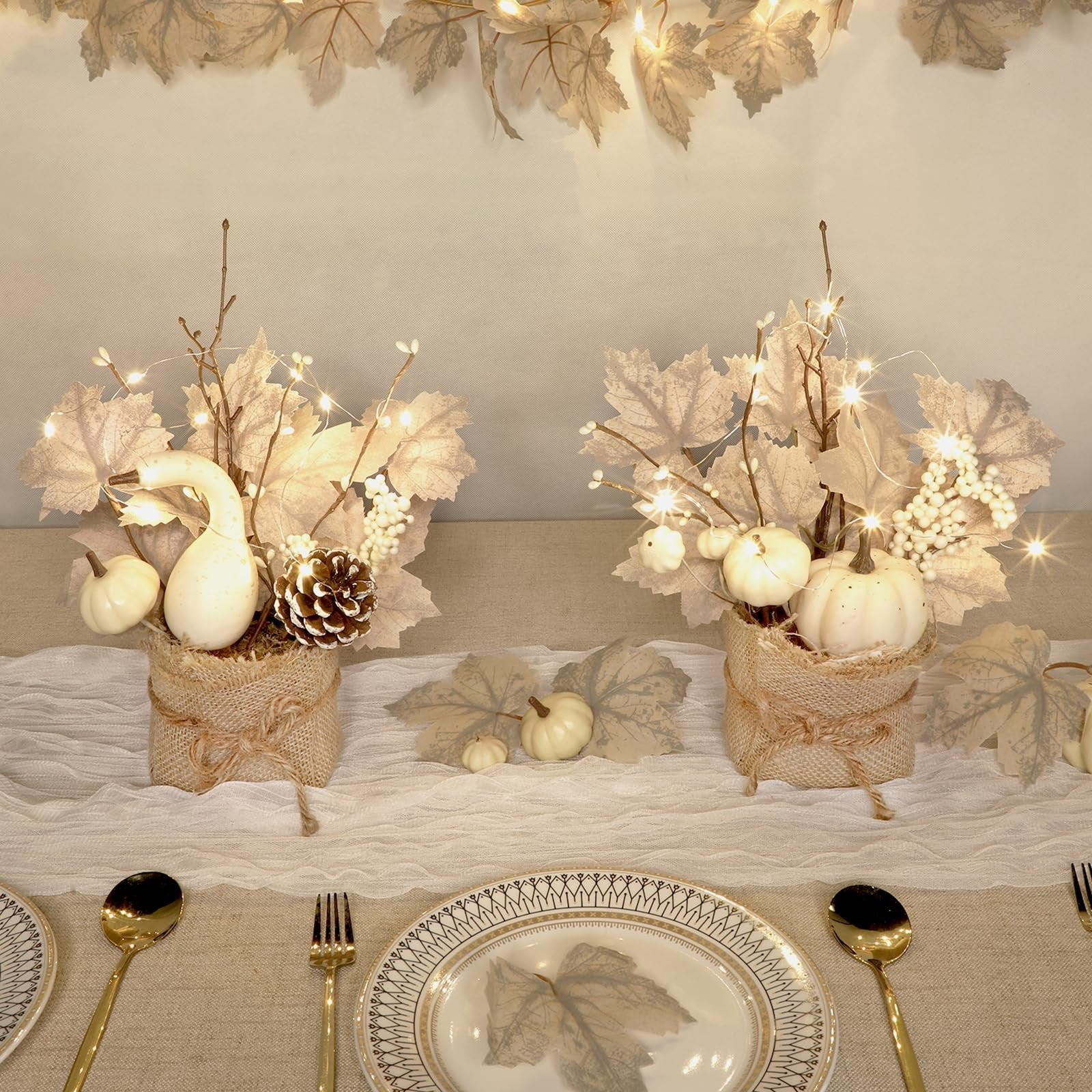Two pre-lit artificial maple trees with LED lights, pumpkins, pinecones, and berries arranged on a table setting.