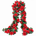 Two strands of artificial red rose garland with green leaves, draped against a white background.