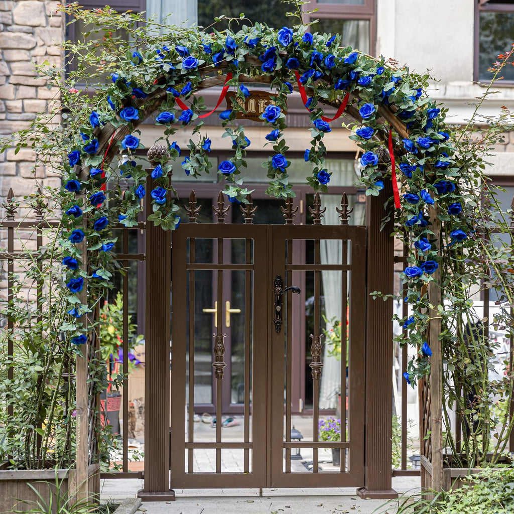 Artificial royal blue rose vine garland draped over a wooden archway and brown metal gate