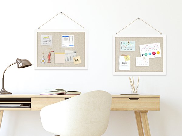Two linen cork boards with white wood frames hanging on a wall above a desk, decorated with notes and charts.