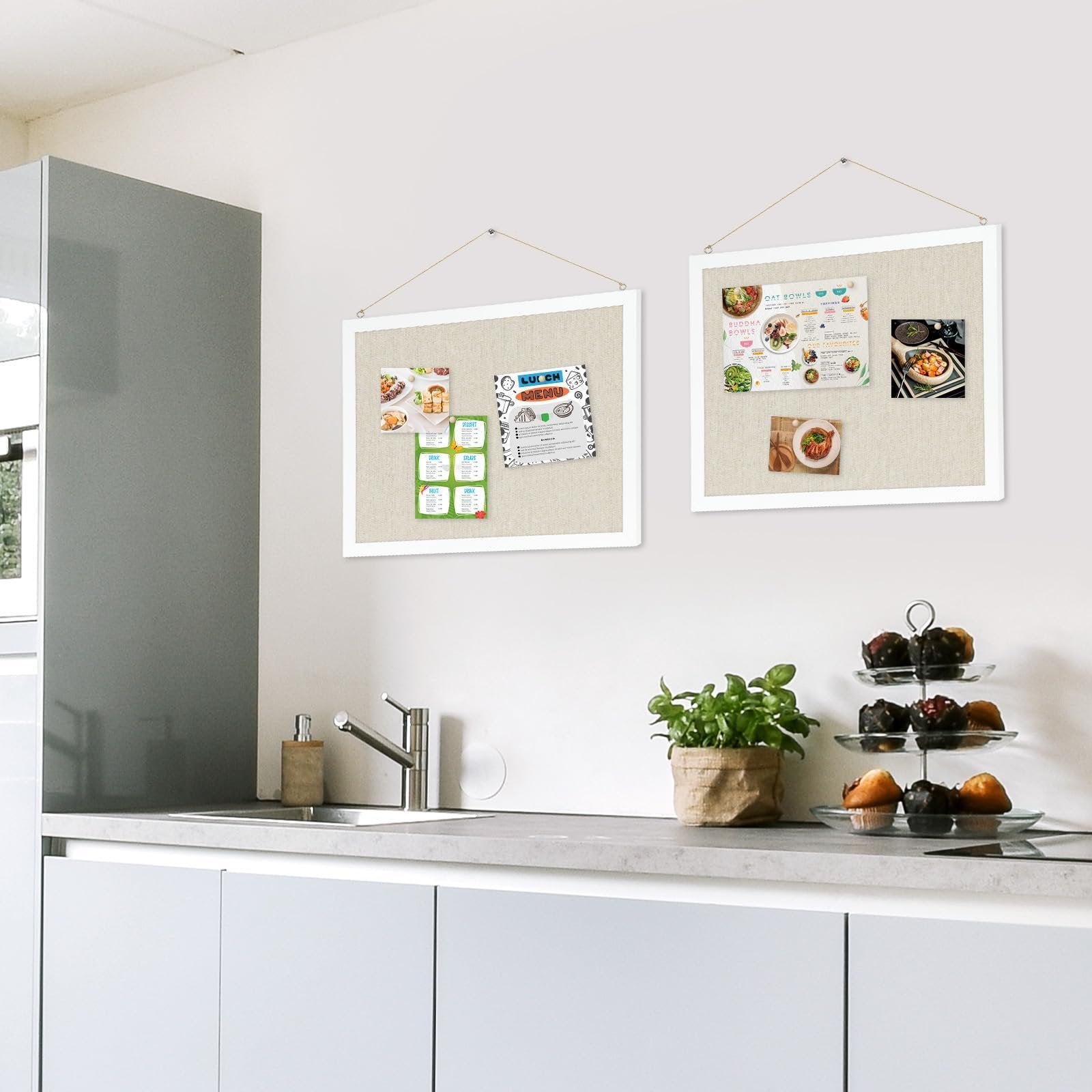 Two linen cork boards with white frames hanging on a kitchen wall, displaying various photos and menus.
