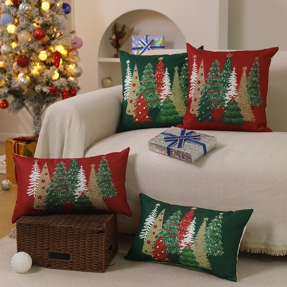 Four Christmas-themed pillow covers with glittery trees displayed on a sofa next to a decorated Christmas tree.