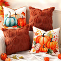 Four decorative throw pillows with fall pumpkin designs and textured pumpkin patterns arranged on a couch.