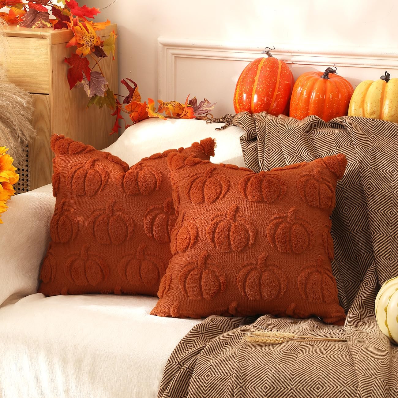 Two rust orange faux fur pumpkin throw pillow covers with textured pumpkin designs are displayed on a couch with fall decor.