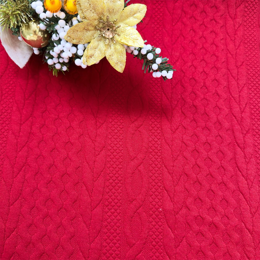 Red Christmas pillow cover with embossed knit texture and festive holiday garland in the upper left corner.