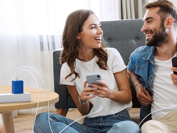 Couple using smartphones while charging devices with a blue dual-port USB C wall charger