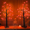 Two Halloween birch trees with 48 orange LED lights and a skeleton figure between them, decorated with spiderwebs.