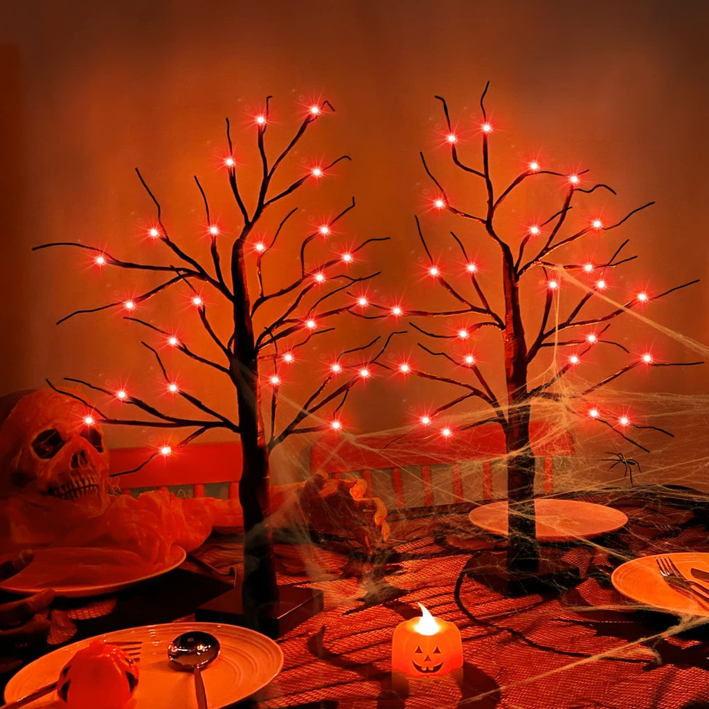 Two Halloween birch trees with 48 orange LED lights on a decorated table with a skull and spiderwebs.