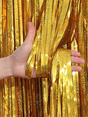 Hand holding a bunch of gold foil fringe streamers, showing texture and sparkle.