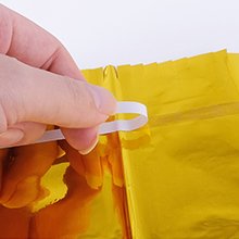 Hand holding a white elastic band attached to a gold foil fringe backdrop curtain