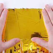 Hands holding a gold foil fringe backdrop curtain against a white background