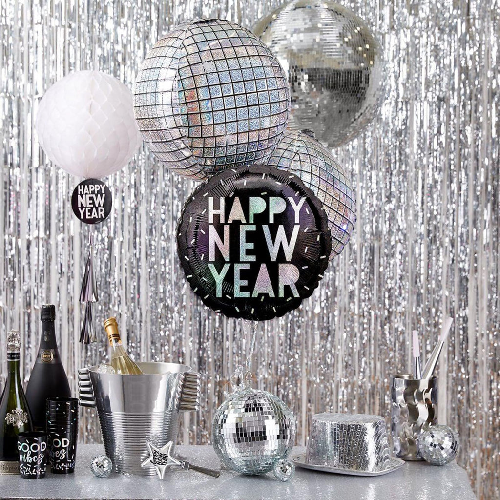 New Year's Eve party scene with disco balls, champagne, and foil fringe backdrop.