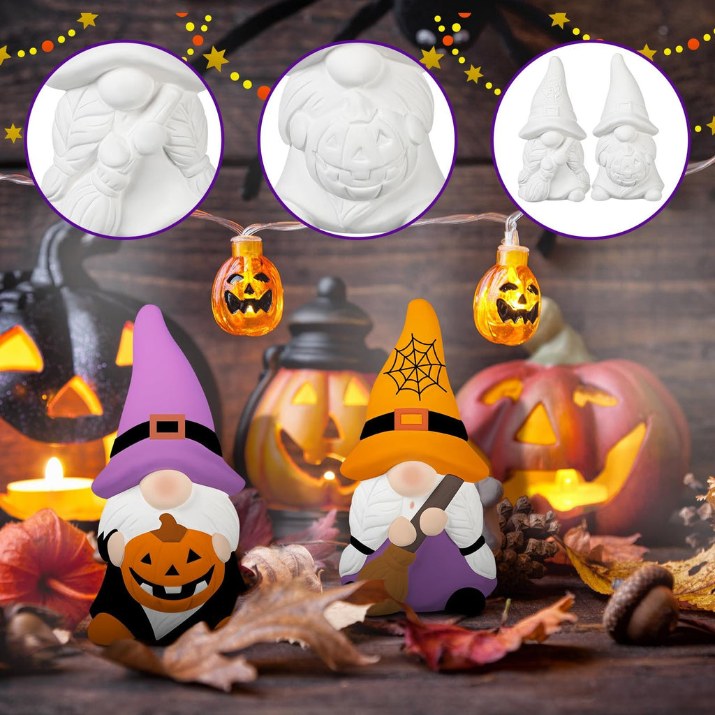 Two ceramic Halloween gnomes, one with a pumpkin and purple hat, the other with a broom and orange hat, on a wooden surface with pumpkins and autumn leaves.