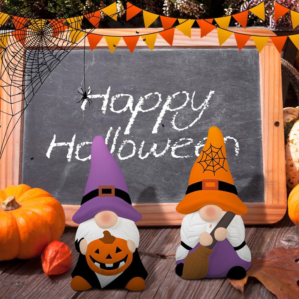 Two Halloween gnomes sit in front of a chalkboard with 'Happy Halloween' written on it, surrounded by pumpkins and fall leaves.