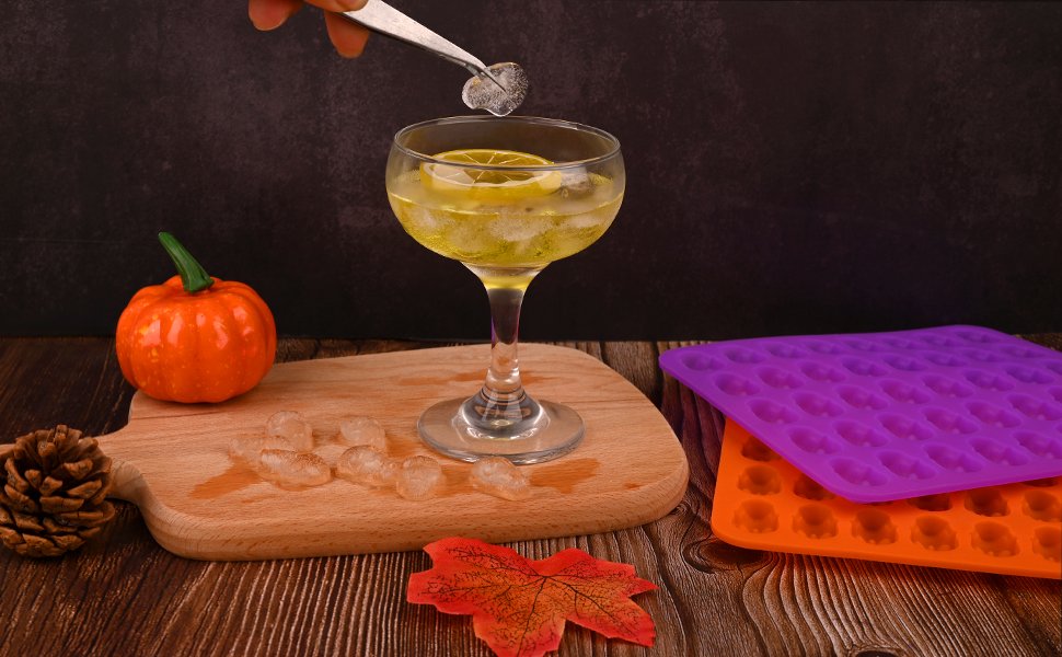 Two silicone candy molds, one purple and one orange, with 40 skull cavities each, shown with a drink and ice.